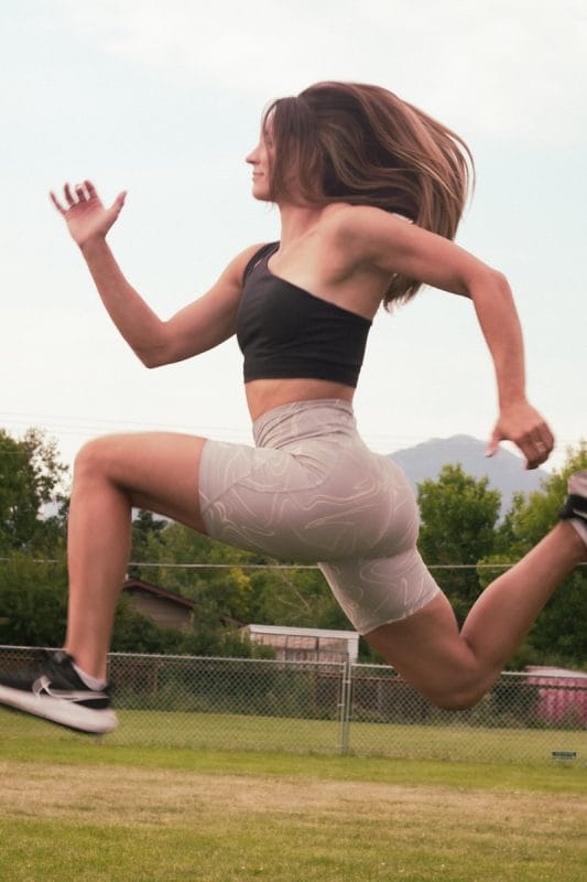 A woman is jumping in the air with a tennis racket